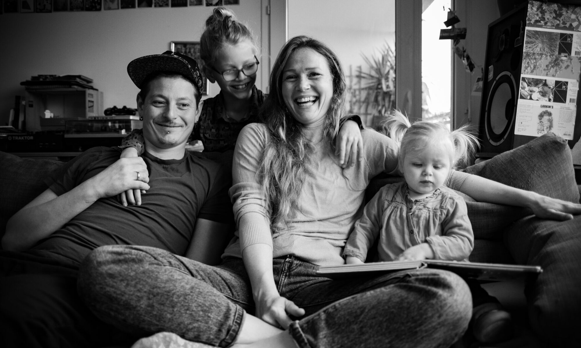 Photo en noir et blanc pour illustrer une prestation de service photo de famille. On y voit un instant de vie d'un couple avec ses deux jeunes enfants.